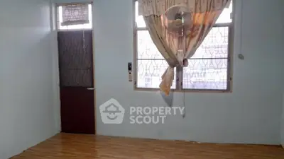 Simple room with wooden flooring and large window, ideal for customization.