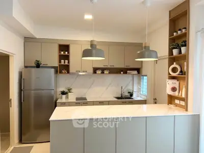 Modern kitchen with sleek cabinetry, marble countertops, and stainless steel fridge, ideal for culinary enthusiasts.