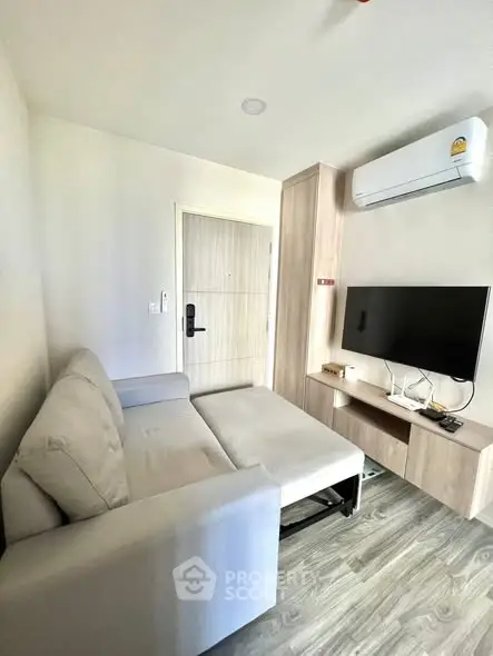 Modern living room with sleek sofa, TV, and air conditioning in a cozy apartment.