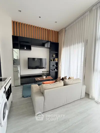 Modern living room with sleek design, featuring a cozy sofa, wall-mounted TV, and washing machine.