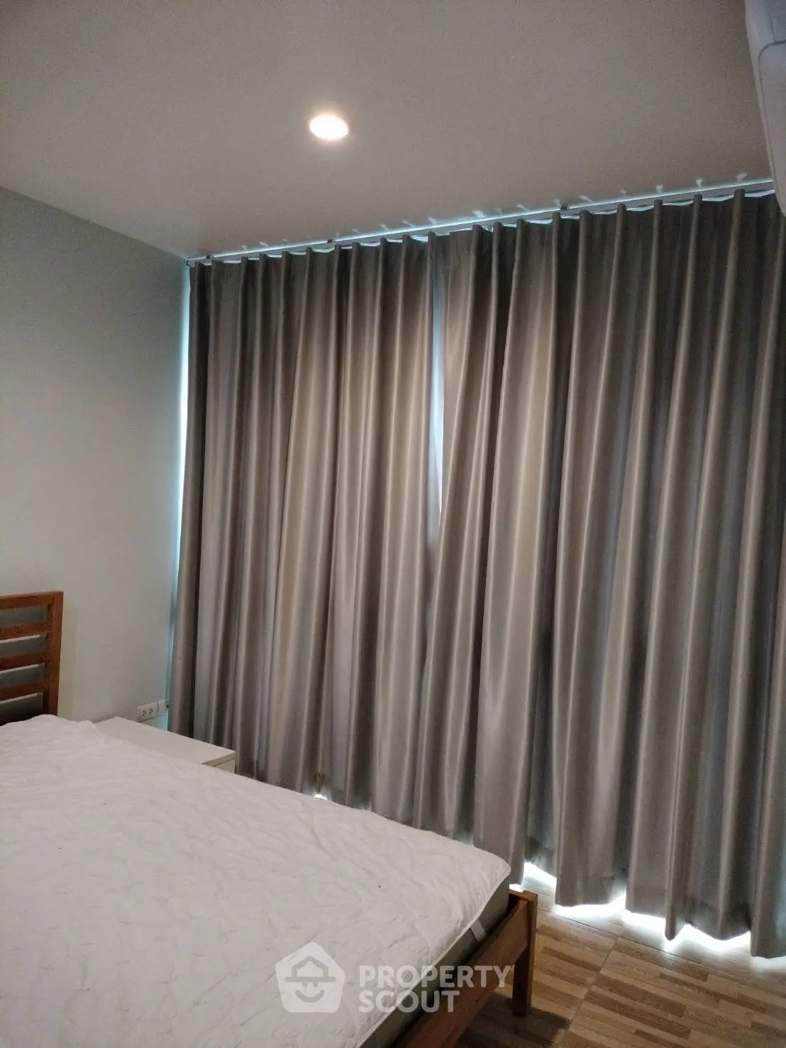 Cozy bedroom with modern curtains and wooden bed frame, perfect for relaxation.