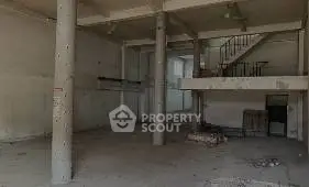 Spacious industrial-style open space with concrete pillars and mezzanine.