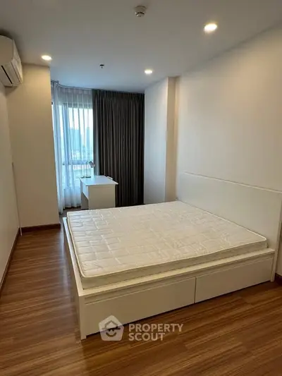 Spacious bedroom with modern design and large window offering natural light.