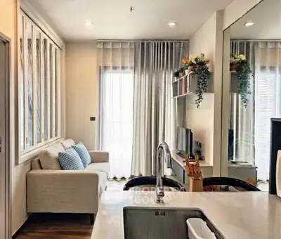 Modern living room with cozy sofa and stylish decor, featuring large windows and elegant curtains.