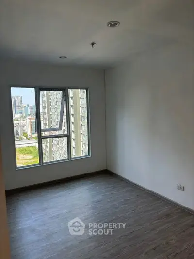 Spacious empty room with large window offering city views, perfect for customization.