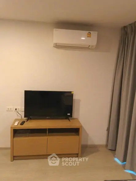 Modern living room with air conditioner and TV on wooden stand.