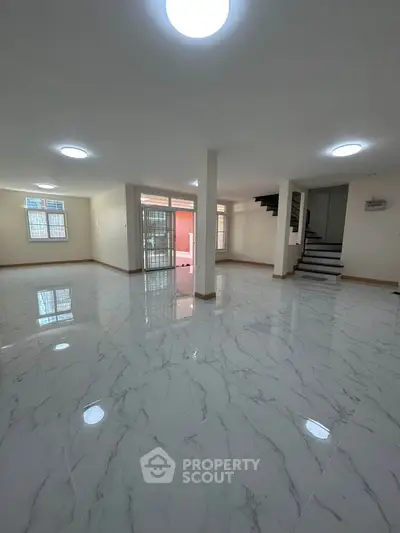 Spacious open-plan living area with elegant marble flooring and modern staircase.