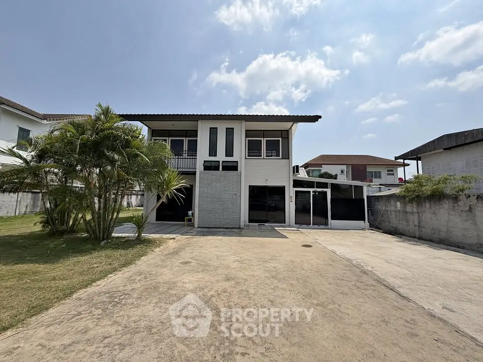 Spacious two-story house with large driveway and lush greenery, perfect for family living.