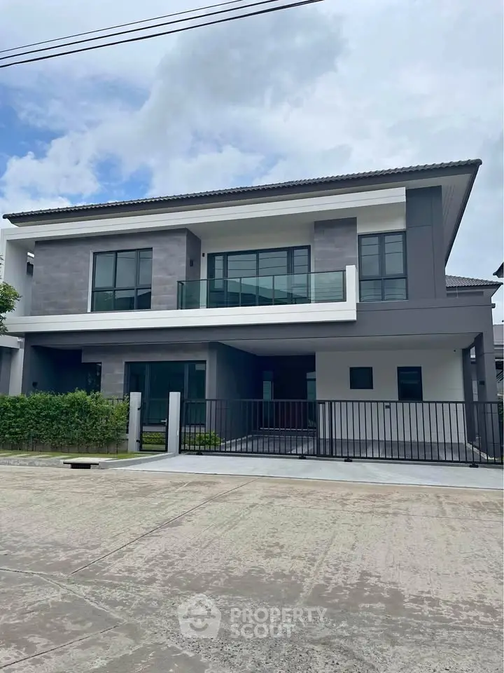 Modern two-story house with sleek design and spacious balcony in suburban neighborhood.