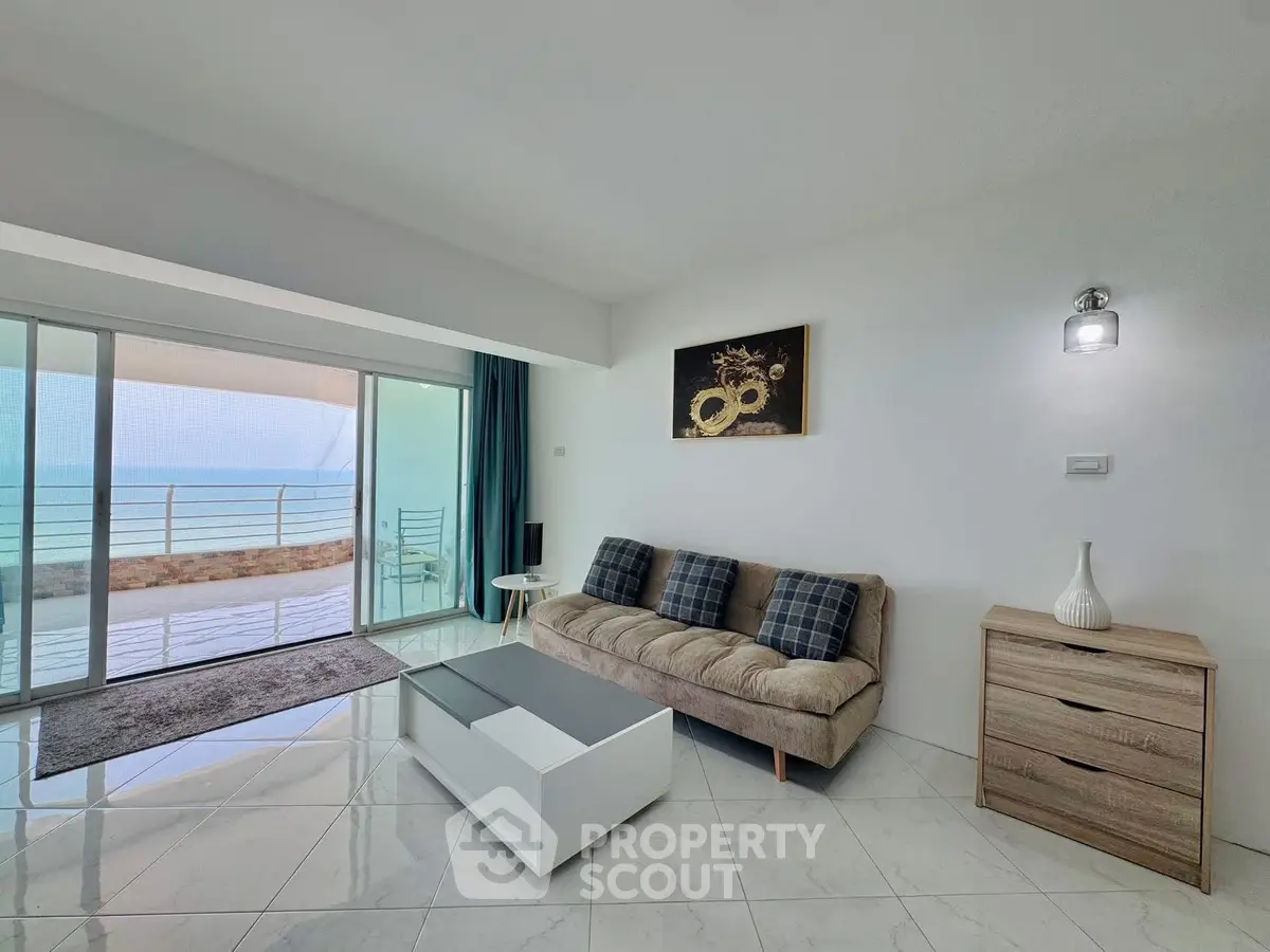Modern living room with ocean view, sleek furniture, and large glass doors leading to a spacious balcony.