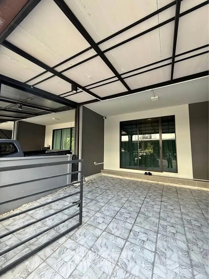 Modern home exterior with tiled patio and large windows, perfect for outdoor relaxation.