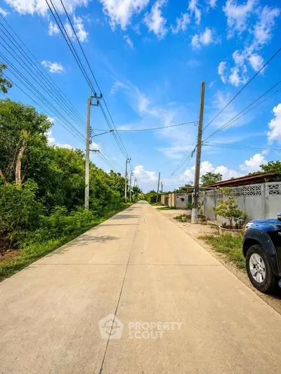Scenic view of a suburban street with clear blue skies and lush greenery, perfect for peaceful living.