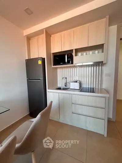 Modern kitchen with sleek cabinetry and appliances in a cozy apartment setting.