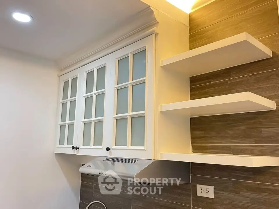 Modern kitchen with white cabinets and open shelves, featuring a sleek range hood.