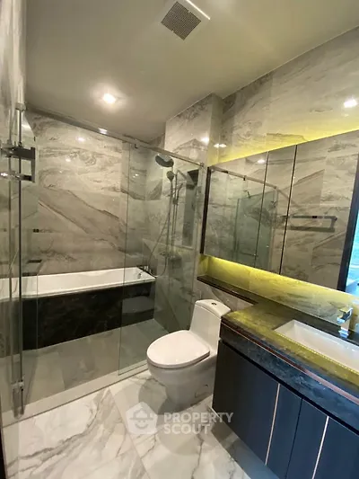 Luxurious modern bathroom with marble tiles and glass shower enclosure