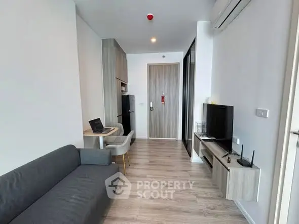 Modern living room with sleek furniture and open layout, featuring a cozy sofa and wall-mounted TV.
