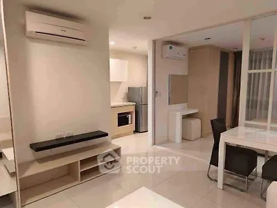 Modern open-plan living area with sleek kitchen and dining space, featuring air conditioning and contemporary design.