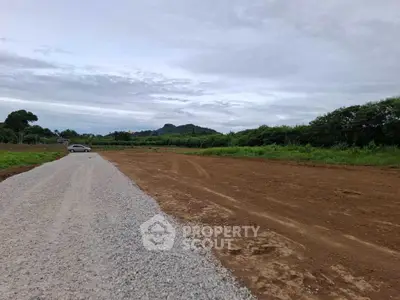 Expansive land plot with gravel road and lush greenery, ideal for development opportunities.