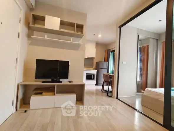 Modern apartment interior with open living room and kitchen, featuring sleek furniture and wooden flooring.