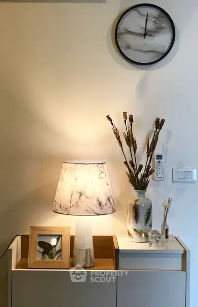 Stylish interior decor with marble lamp, clock, and modern accents in a cozy living space.