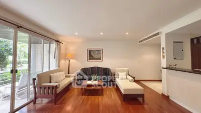 Spacious living room with elegant wooden flooring and large windows overlooking greenery.