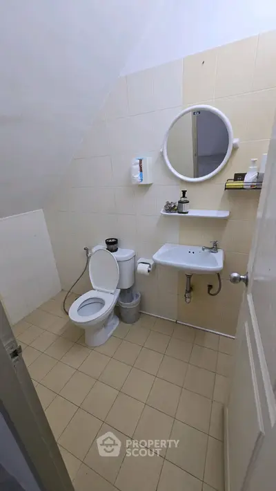 Compact bathroom with round mirror and wall-mounted sink in a cozy home.