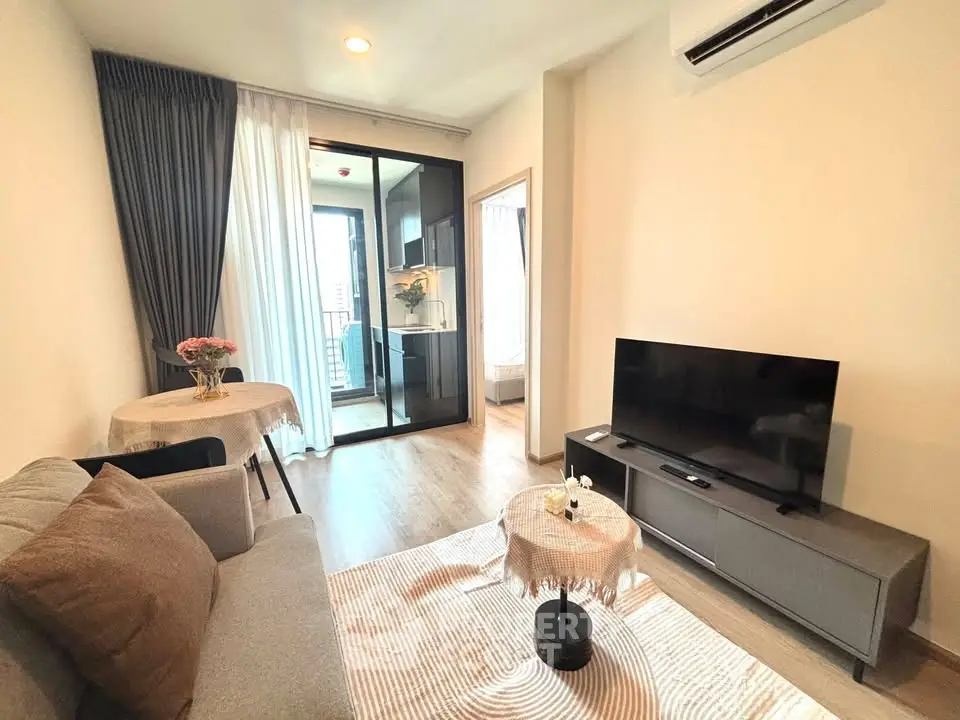 Modern living room with balcony access, featuring sleek furniture and natural light.