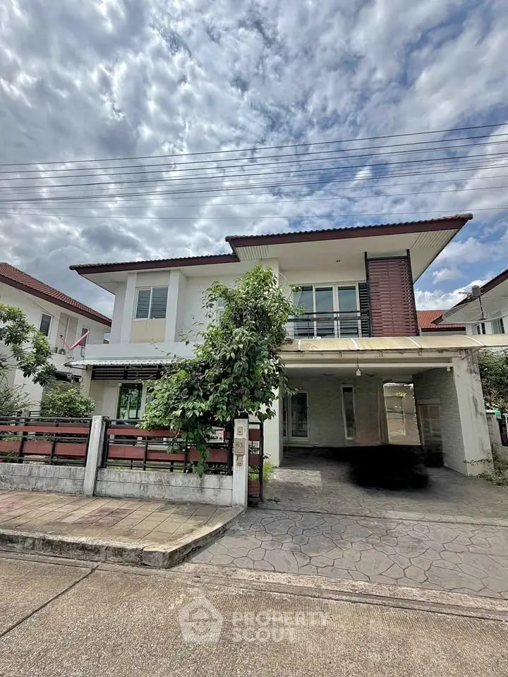 Charming two-story house with a spacious driveway and lush greenery, perfect for family living.
