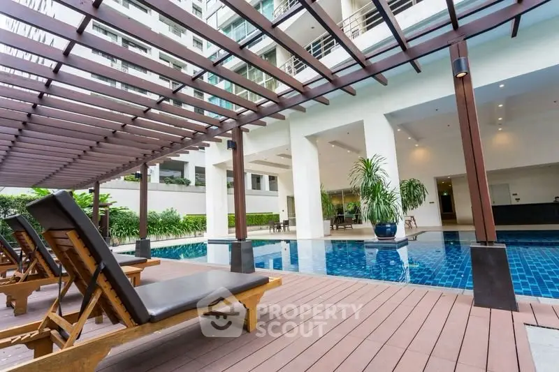 Luxurious apartment complex with stunning poolside lounge area and modern architecture.