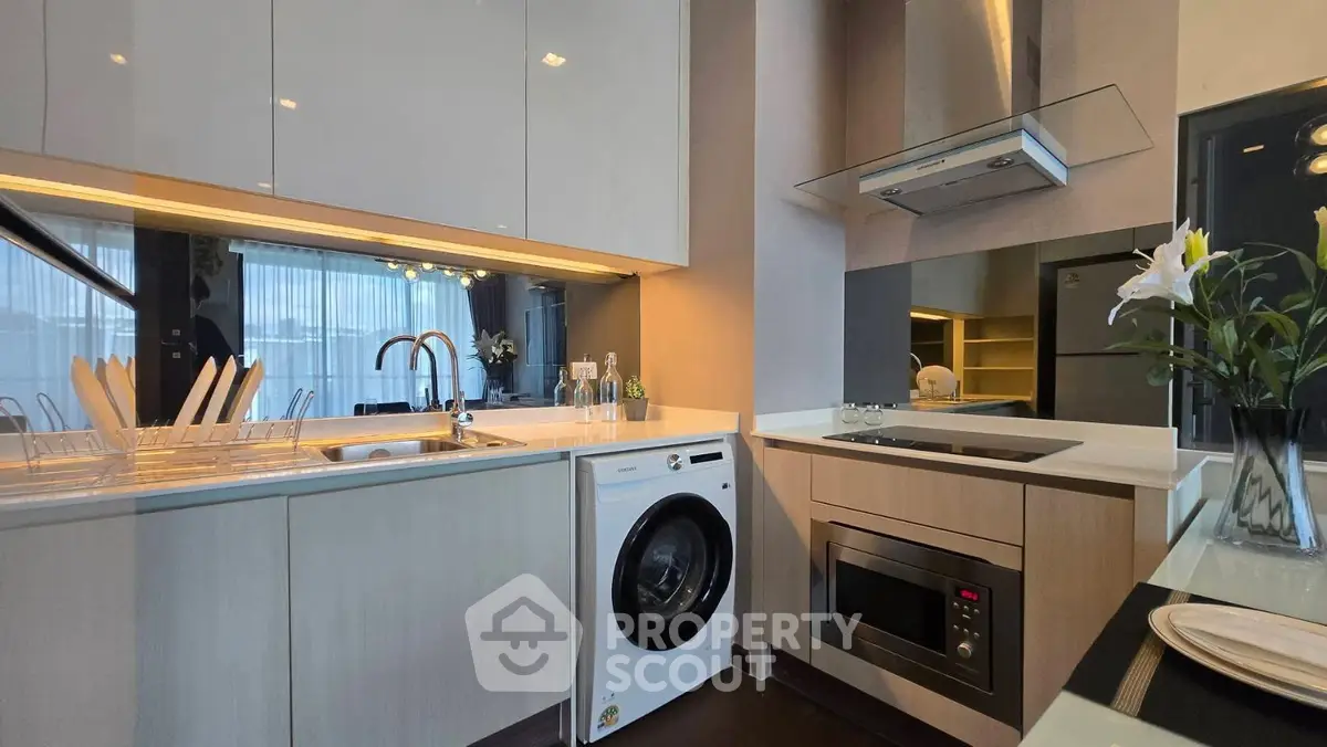Modern kitchen with sleek cabinetry, washing machine, and built-in appliances