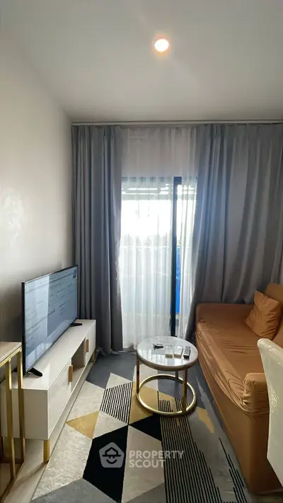 Modern living room with stylish decor and natural light, featuring a cozy sofa and sleek TV setup.
