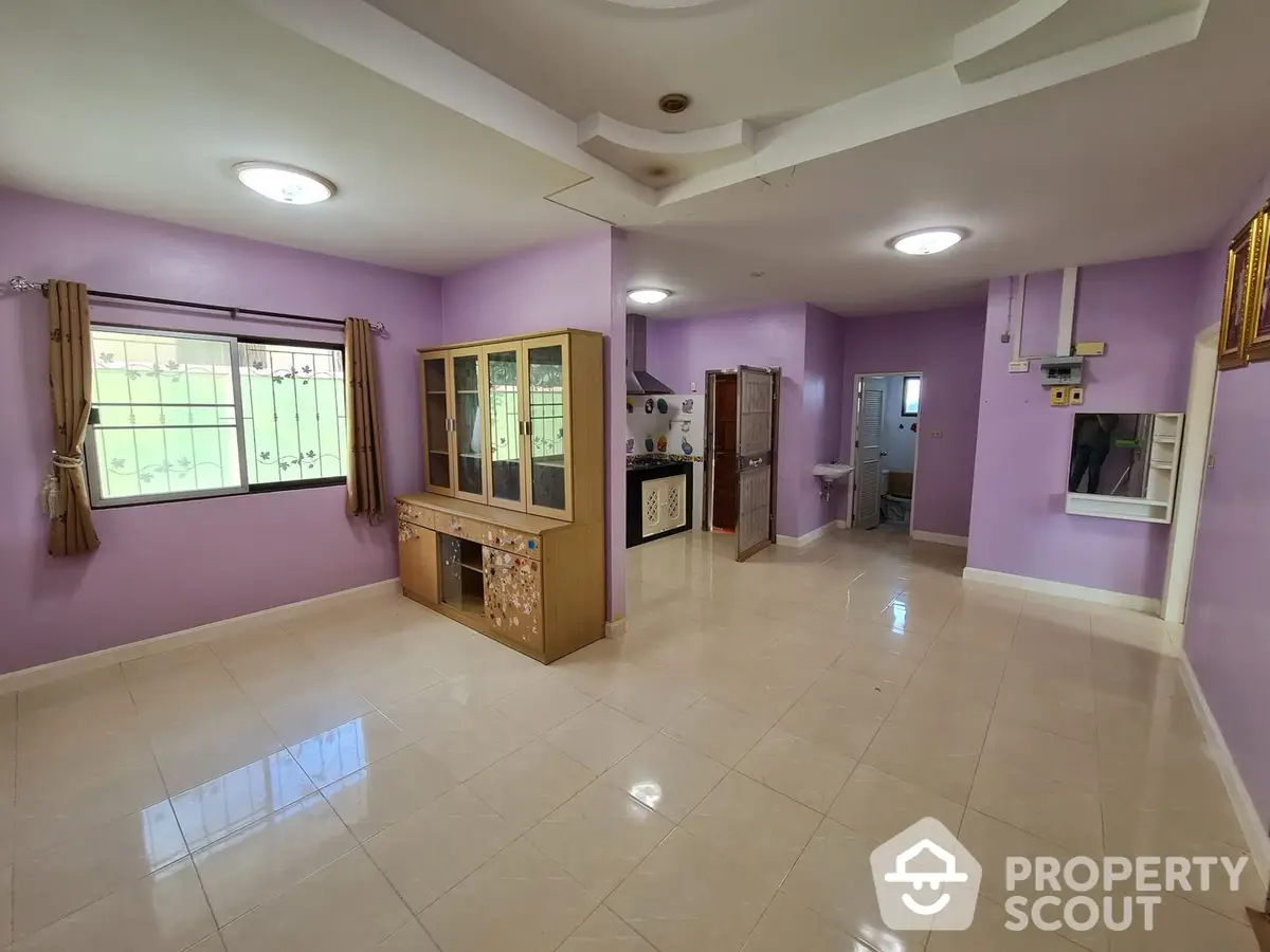 Spacious living area with glossy tiled flooring, lavender walls, and ample natural light streaming through multiple windows, perfect for family gatherings.