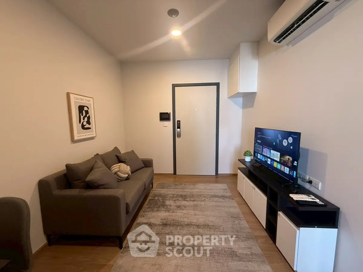 Modern living room with cozy sofa, wall art, and flat-screen TV in stylish apartment.
