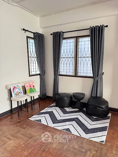 Cozy corner with stylish rug and seating in a bright room with large windows.