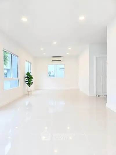Spacious modern living room with bright white tiles and large windows.