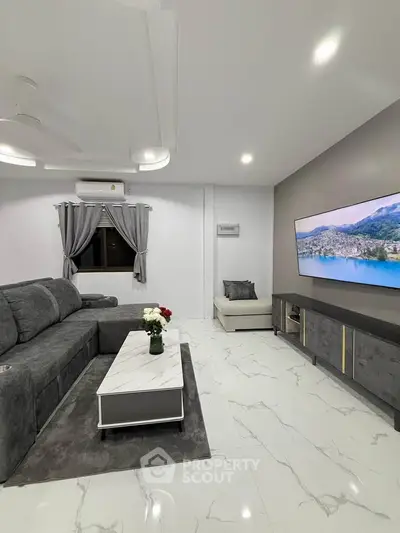 Modern living room with sleek gray sofa, marble coffee table, and wall-mounted TV in stylish apartment.