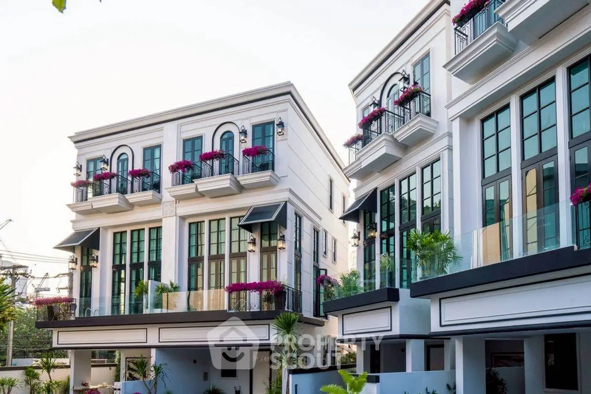 Elegant modern townhouses with large windows and balconies adorned with flowers.