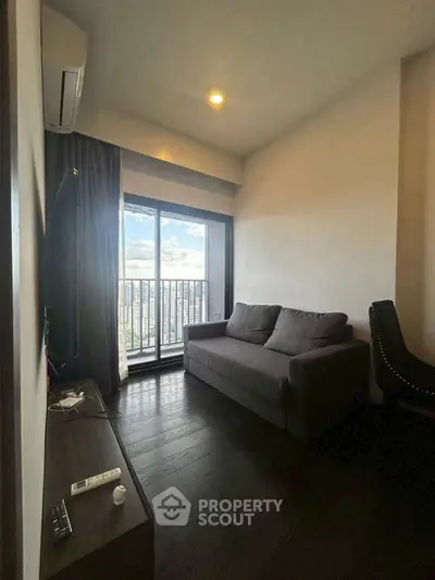 Cozy living room with dark wood floors and city view balcony.