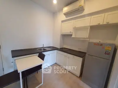 Modern kitchen with sleek design, featuring white cabinets and compact dining area.