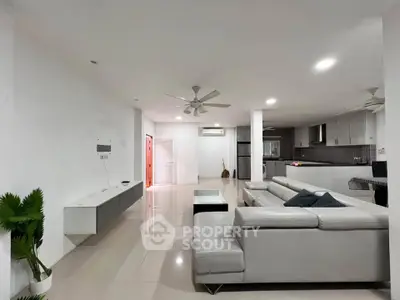 Spacious modern living room with sleek furniture and open kitchen layout, perfect for contemporary living.