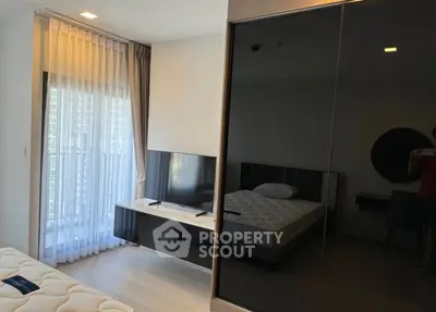 Modern bedroom with sleek furniture and large window offering natural light.