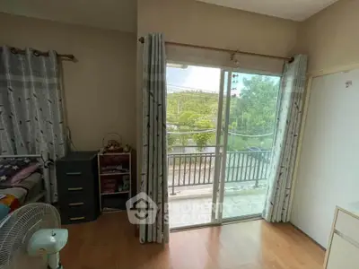 Bright bedroom with balcony access and garden view, featuring sliding glass doors and wooden flooring.