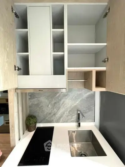 Modern compact kitchen with sleek cabinetry and electric cooktop