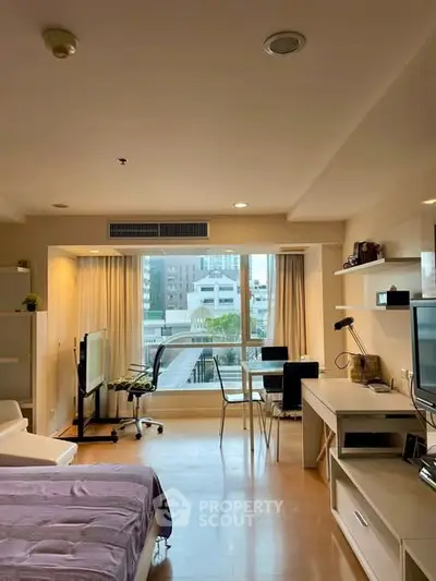 Modern studio apartment with city view, featuring sleek furniture and ample natural light.