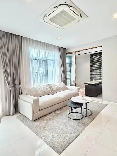 Elegant living room with plush sofa, modern decor, and natural light through large windows.