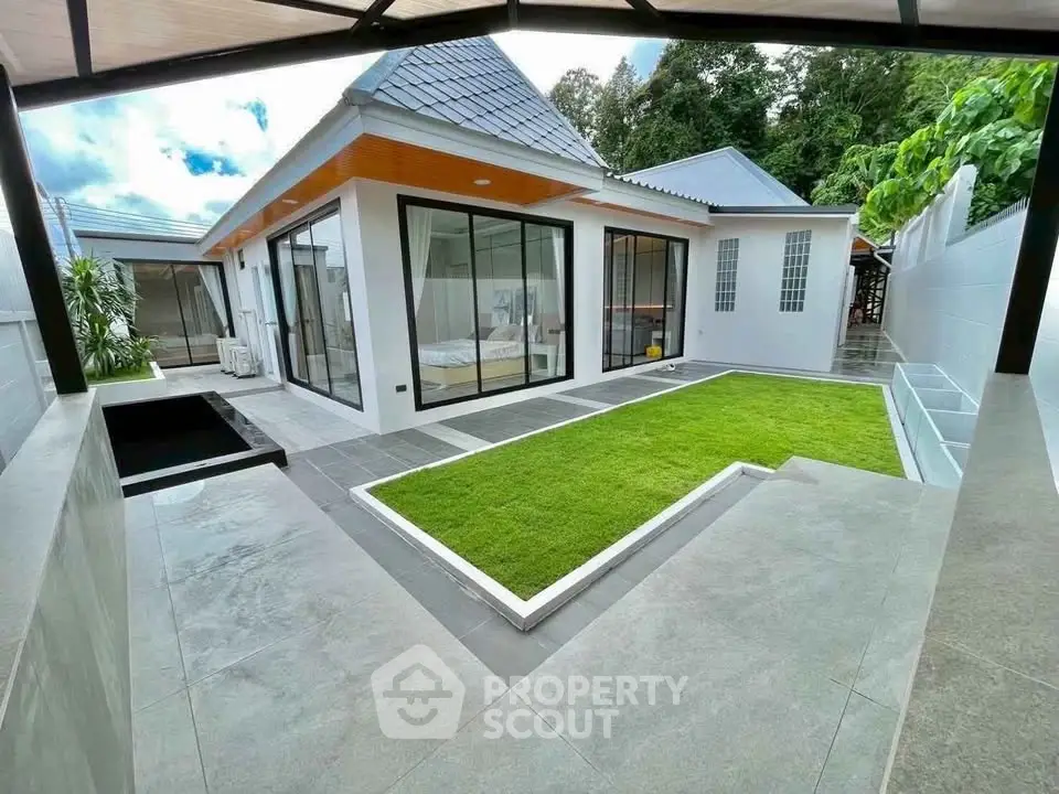 Modern villa with sleek design and lush green lawn, featuring large glass doors and contemporary architecture.