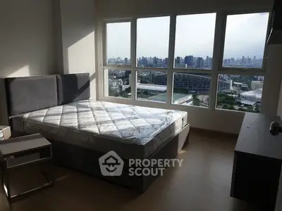 Spacious bedroom with large windows offering a stunning city view, perfect for urban living.
