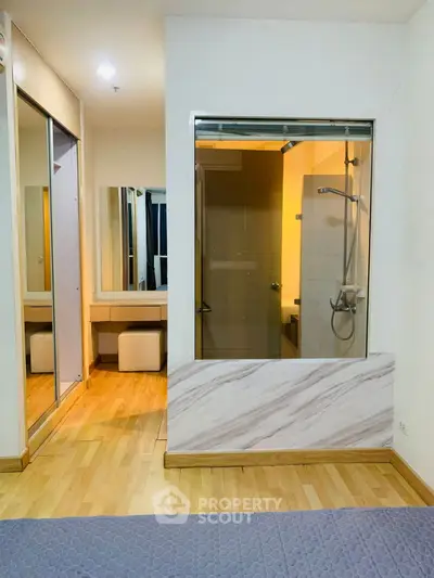 Modern bedroom with glass-enclosed shower and wooden flooring