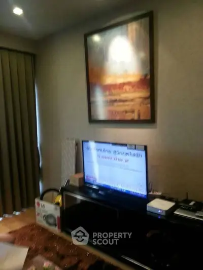 Cozy living room with modern decor and wall art, featuring a flat-screen TV and elegant lighting.