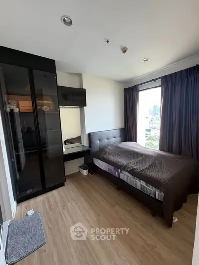 Modern bedroom with city view, featuring sleek black wardrobe and cozy bed in a high-rise apartment.